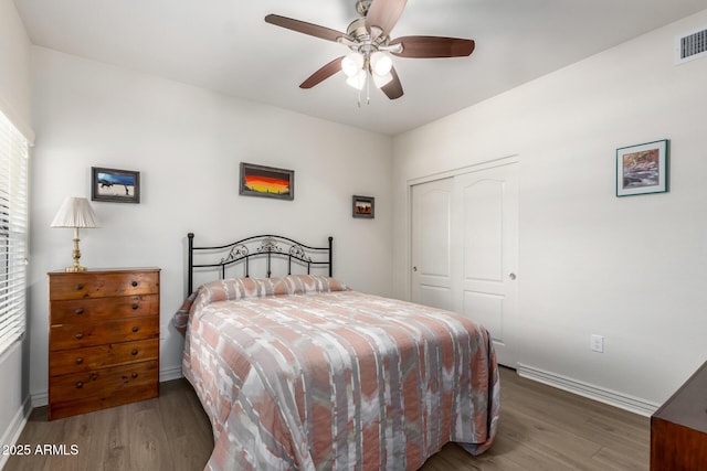 bedroom with dark wood-type flooring, a closet, and ceiling fan