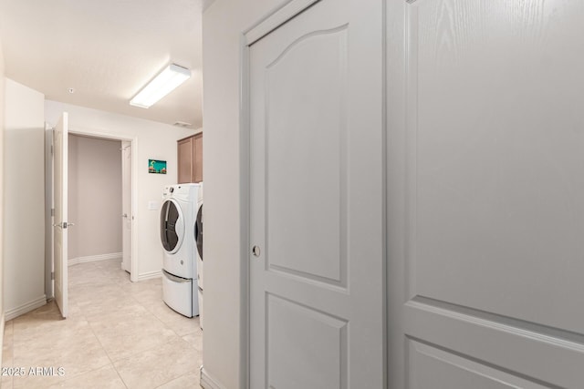 laundry area with separate washer and dryer, cabinets, and light tile patterned flooring