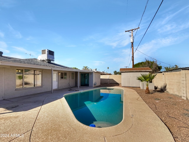 view of pool with central air condition unit, a patio area, and a storage shed