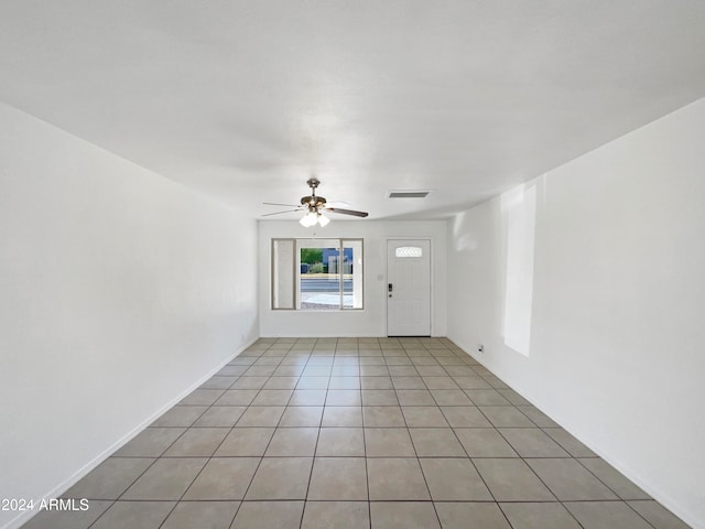 empty room with ceiling fan and light tile patterned floors