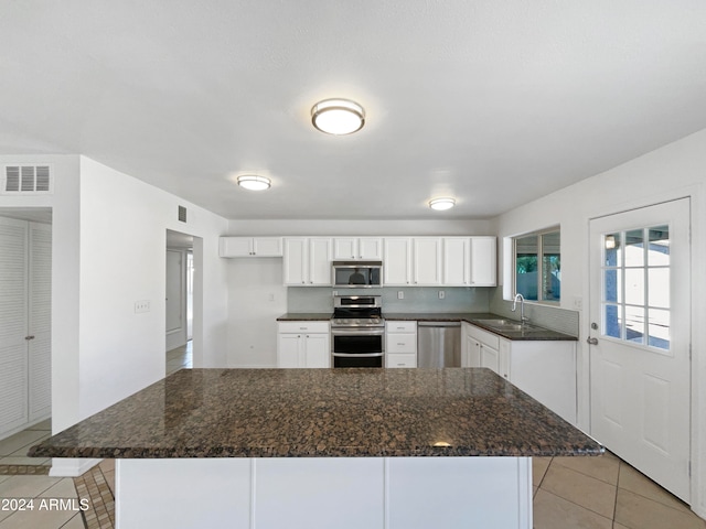 kitchen with sink, appliances with stainless steel finishes, white cabinetry, and light tile patterned floors