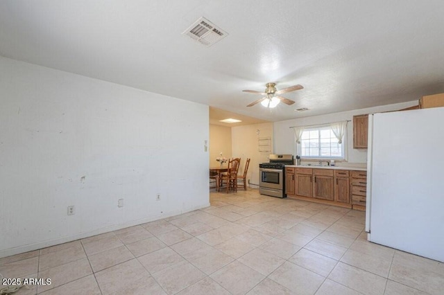 1055 S 4th St, Coolidge, AZ 85128 - interior space with stainless steel gas range, visible vents, freestanding refrigerator, a ceiling fan, and light countertops