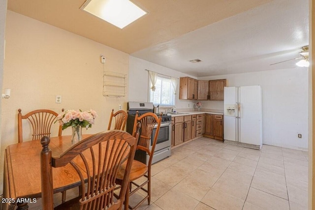1055 S 4th St, Coolidge, AZ 85128 - kitchen featuring brown cabinetry, stainless steel gas range, light tile patterned flooring, white fridge with ice dispenser, and light countertops