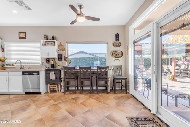 kitchen featuring sink, white cabinetry, light tile patterned floors, stainless steel dishwasher, and ceiling fan