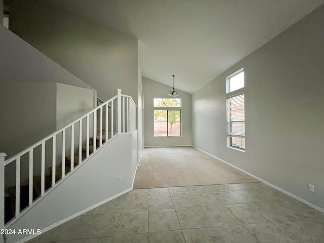 tiled spare room featuring vaulted ceiling and an inviting chandelier