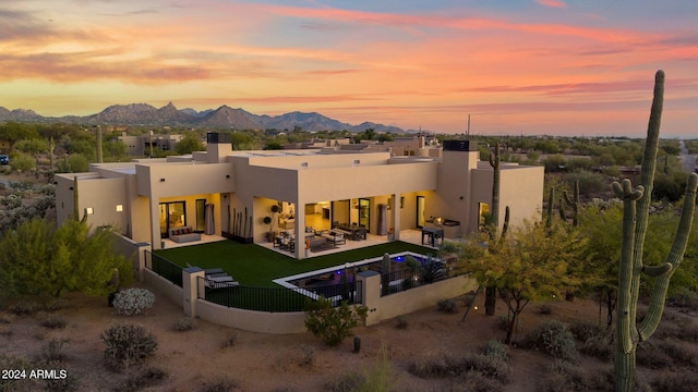 back house at dusk with a mountain view, a yard, a patio, and an outdoor hangout area