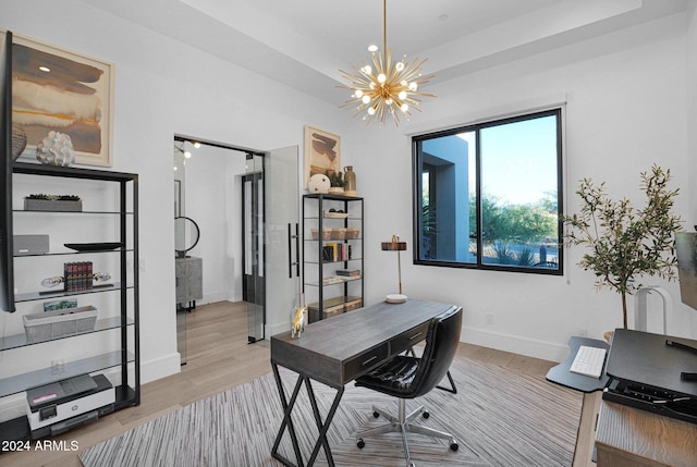 office area with light hardwood / wood-style floors and an inviting chandelier