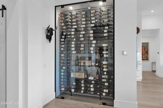 wine area featuring light wood-type flooring, electric panel, and a barn door