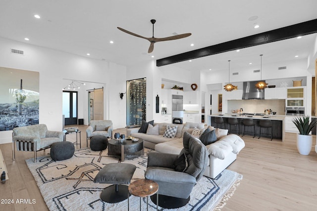 living room with beam ceiling, a towering ceiling, light hardwood / wood-style floors, and ceiling fan