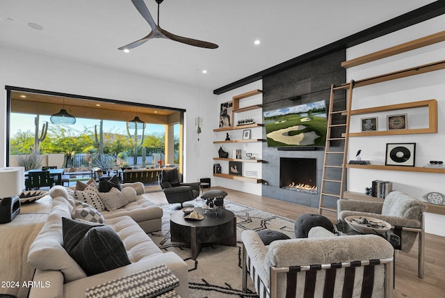 living room featuring a large fireplace, light hardwood / wood-style floors, and ceiling fan