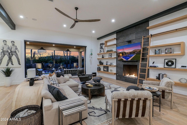 living room featuring ceiling fan, light wood-type flooring, and a tile fireplace