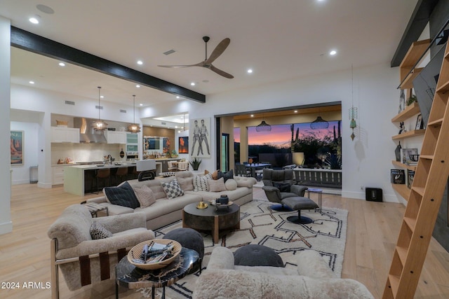 living room featuring beamed ceiling, light wood-type flooring, and ceiling fan