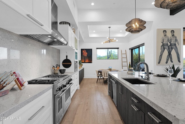 kitchen featuring sink, double oven range, decorative light fixtures, white cabinets, and light wood-type flooring