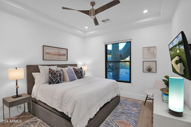 bedroom featuring a raised ceiling, ceiling fan, and wood-type flooring