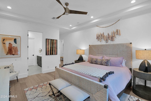 bedroom featuring light hardwood / wood-style floors, ensuite bath, and ceiling fan