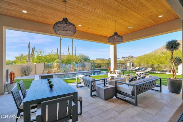 view of patio featuring a fenced in pool, a mountain view, and an outdoor hangout area