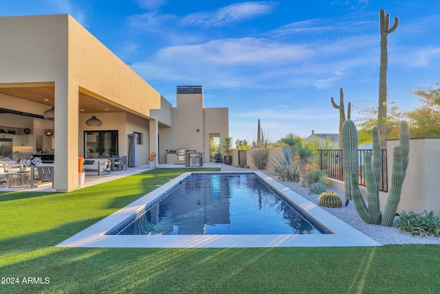 view of pool with a lawn, exterior kitchen, and a patio