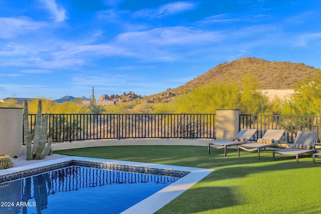 view of swimming pool with a lawn and a mountain view