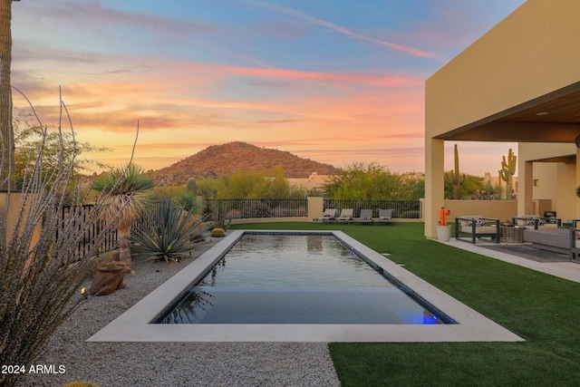 pool at dusk featuring a mountain view and a yard