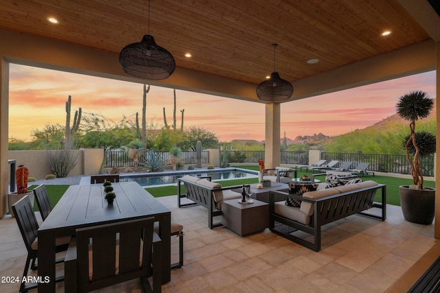 patio terrace at dusk featuring an outdoor living space and a fenced in pool