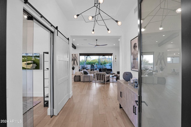 hallway with a chandelier, a barn door, and light hardwood / wood-style flooring