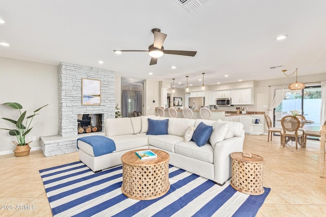 tiled living room with ceiling fan and a fireplace