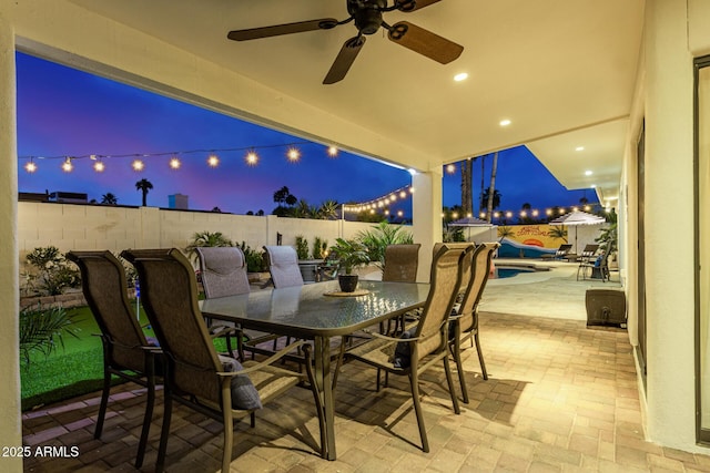 patio terrace at dusk with a fenced in pool and ceiling fan