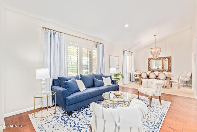 living room featuring vaulted ceiling, hardwood / wood-style floors, and a notable chandelier