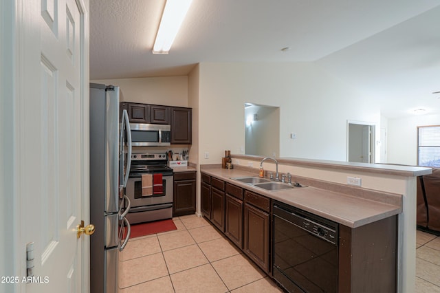 kitchen with stainless steel appliances, sink, kitchen peninsula, vaulted ceiling, and light tile patterned floors