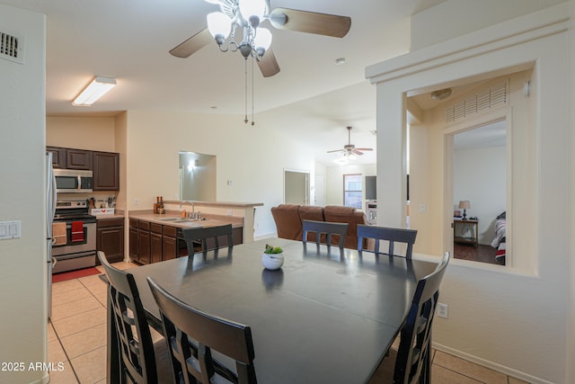 tiled dining room featuring ceiling fan, lofted ceiling, and sink