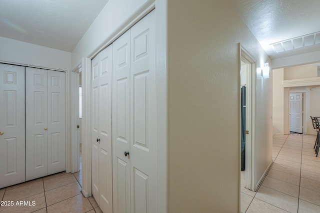 corridor featuring light tile patterned flooring and a textured ceiling