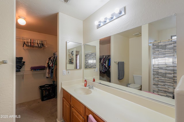 bathroom featuring a textured ceiling, toilet, and vanity