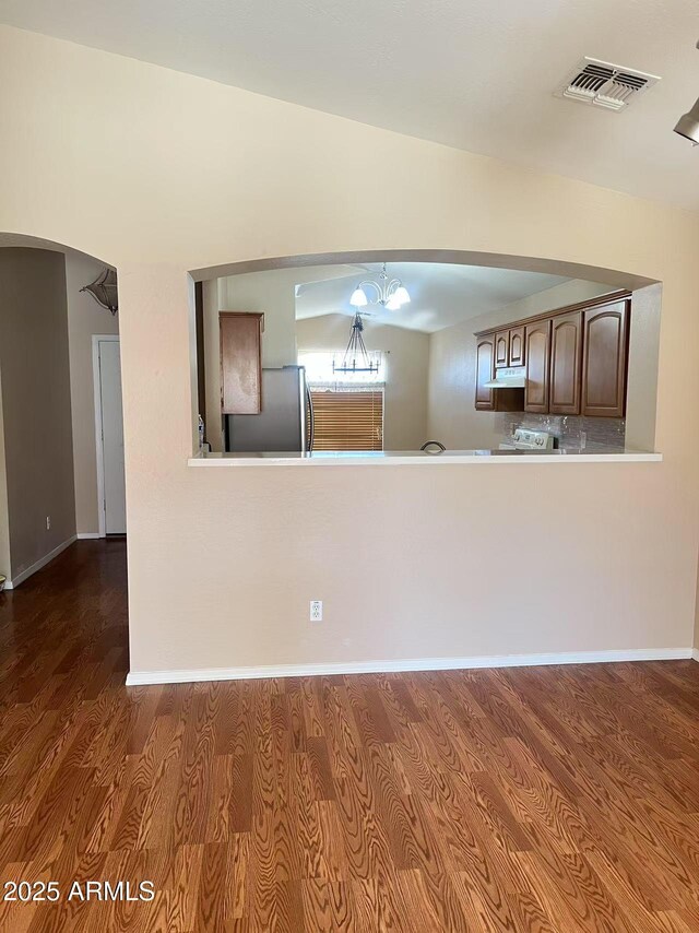 8507 W Pioneer St, Tolleson, AZ 85353 - kitchen with freestanding refrigerator, arched walkways, wood finished floors, under cabinet range hood, and a chandelier
