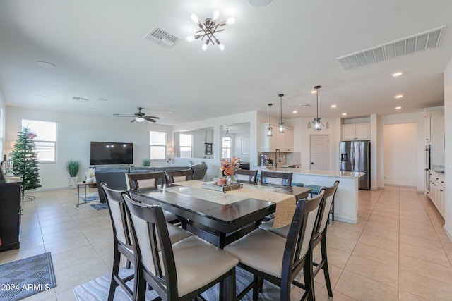 tiled dining room featuring ceiling fan with notable chandelier, a healthy amount of sunlight, and sink