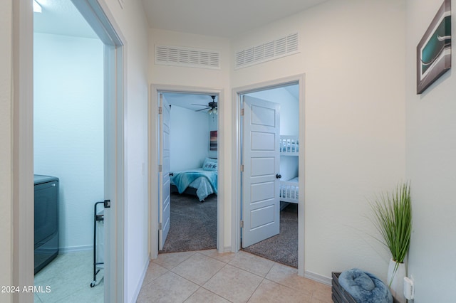 hall featuring light tile patterned floors and independent washer and dryer