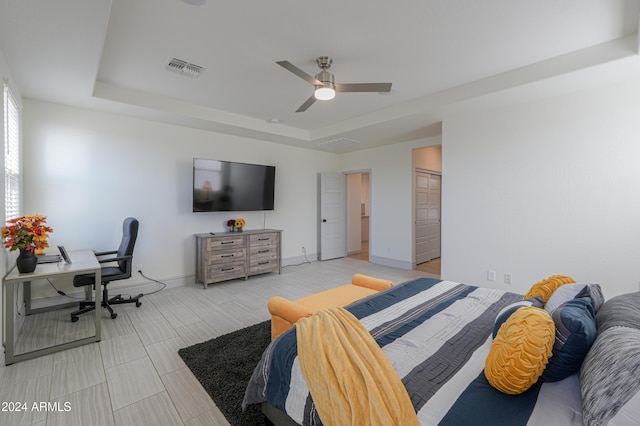 bedroom featuring ceiling fan, a tray ceiling, and a closet