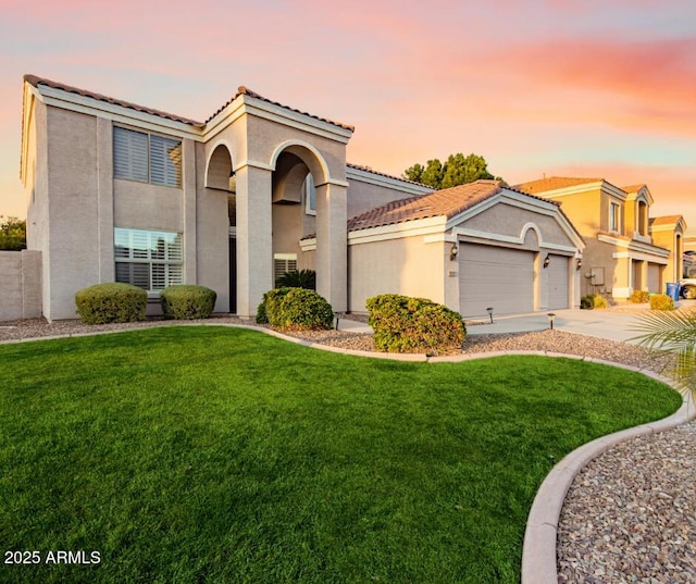 mediterranean / spanish-style home featuring concrete driveway, a tiled roof, a front lawn, and stucco siding