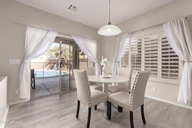 dining space with wood finished floors, visible vents, and baseboards