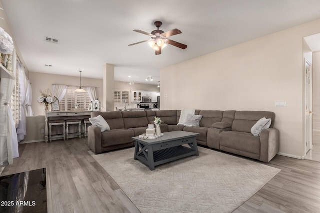 living room with baseboards, visible vents, ceiling fan, and wood finished floors