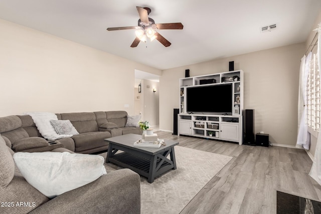 living room featuring light wood finished floors, baseboards, visible vents, and ceiling fan