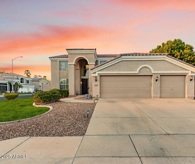 mediterranean / spanish house featuring a garage, driveway, a tile roof, and stucco siding