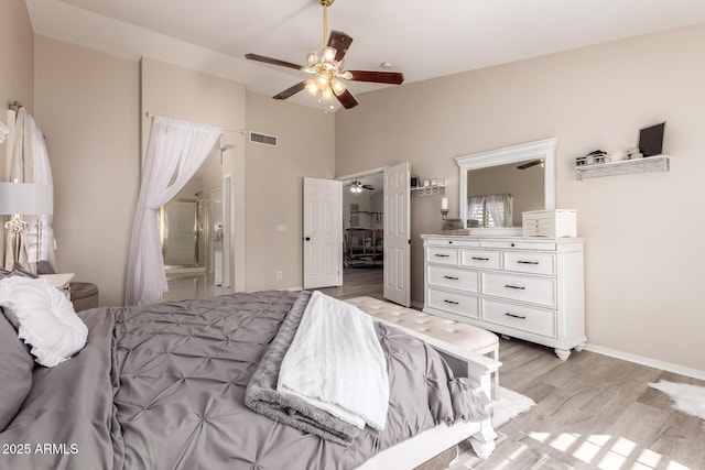 bedroom featuring light wood-type flooring, visible vents, lofted ceiling, and ensuite bath