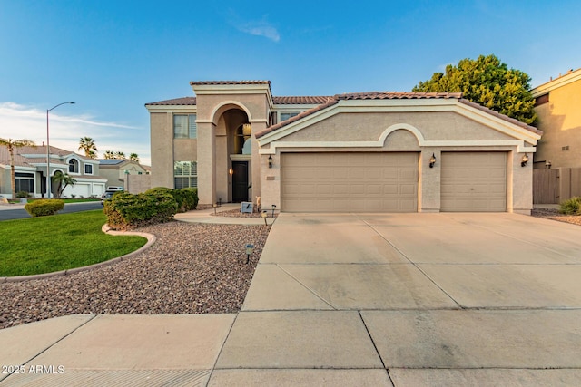 mediterranean / spanish-style house featuring an attached garage, a tile roof, concrete driveway, and stucco siding