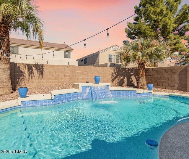 pool at dusk featuring a fenced backyard and a fenced in pool