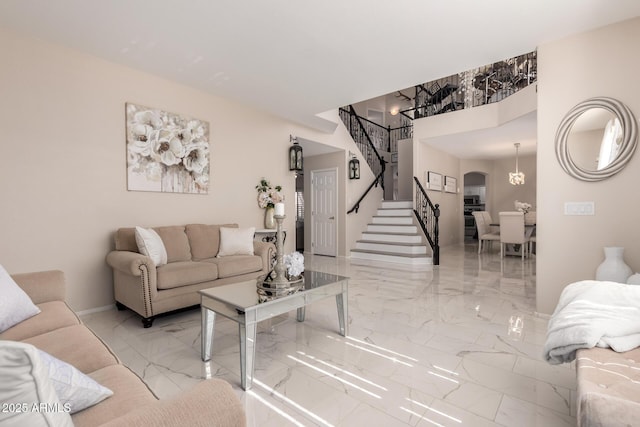 living area featuring arched walkways, marble finish floor, stairway, and baseboards