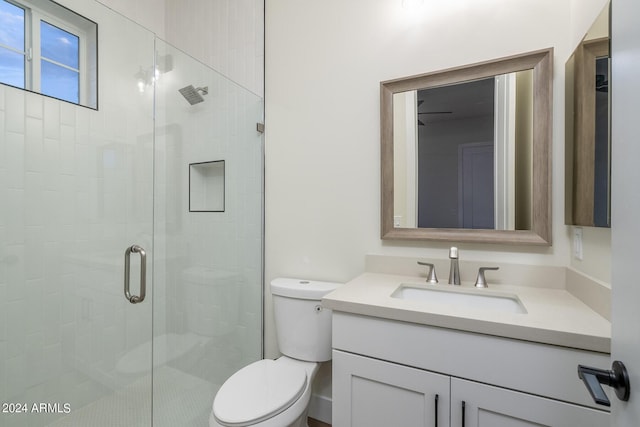 bathroom with a shower with door, vanity, and toilet