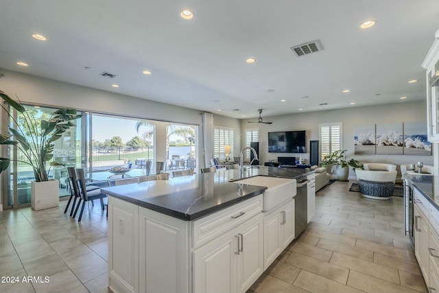 kitchen featuring white cabinets, ceiling fan, sink, and a kitchen island with sink