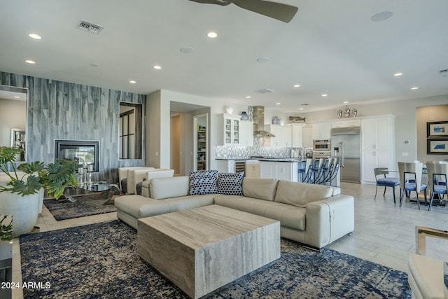 living room featuring ceiling fan, a fireplace, and light tile patterned flooring