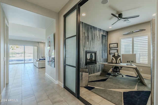 tiled office with a large fireplace, ceiling fan, and a healthy amount of sunlight