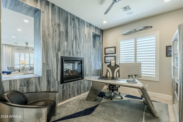 office space featuring ceiling fan, a multi sided fireplace, and tile walls